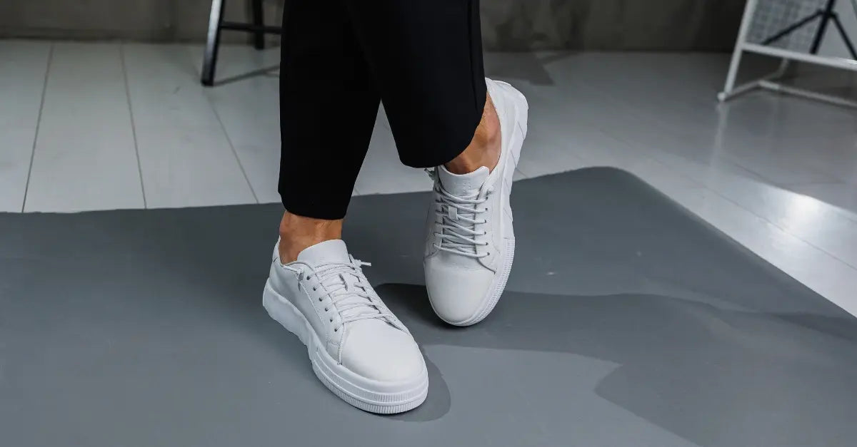 Persona usando zapatillas deportivas blancas sobre suelo interior, mostrando comodidad y estilo casual.