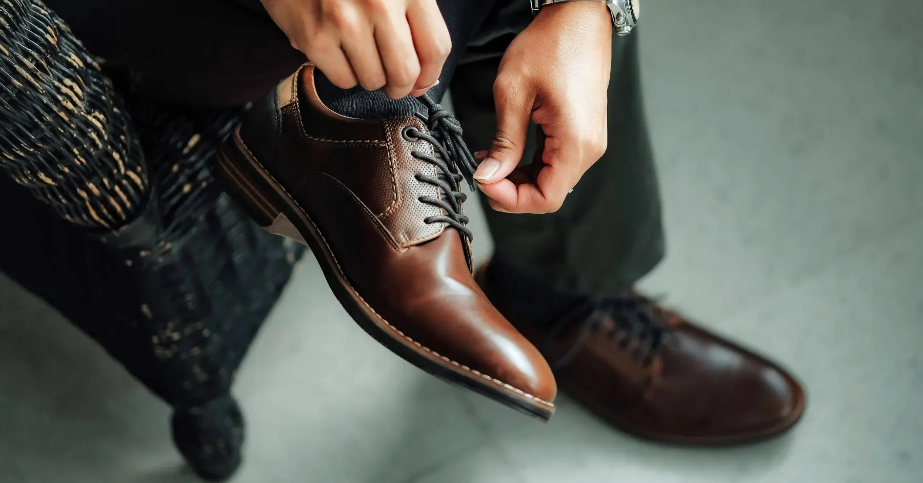 Hombre ajustando zapatos de vestir marrones, ideales para entornos laborales o eventos formales.